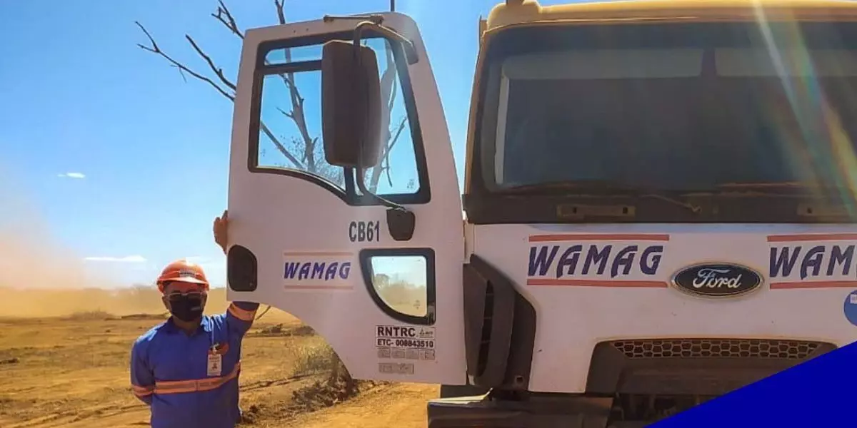 A foto mostra um caminhão e um motorista da Transportes WAMAG