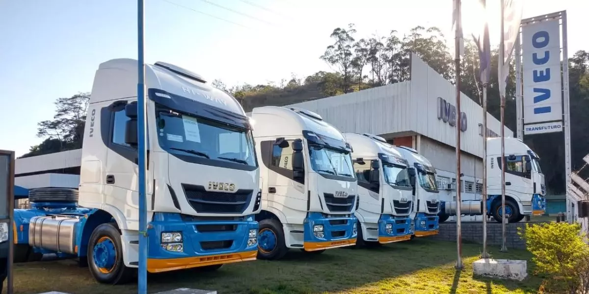 A foto mostra uma frota de caminhões da Transporte Excelsior