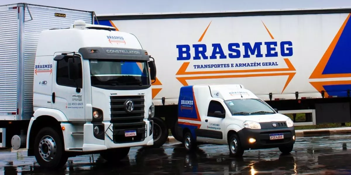 A foto mostra uma frota de veículos e caminhões da Brasmeg Transportes