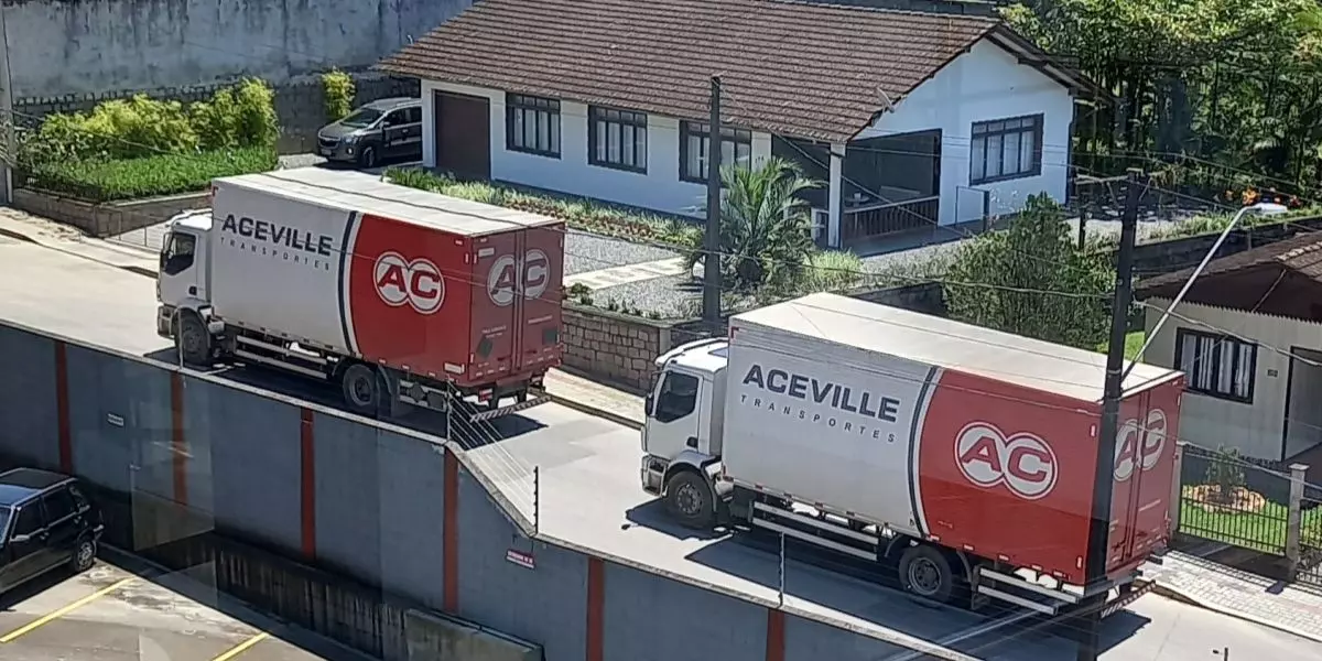 A foto mostra dois caminhões da Aceville Transportes