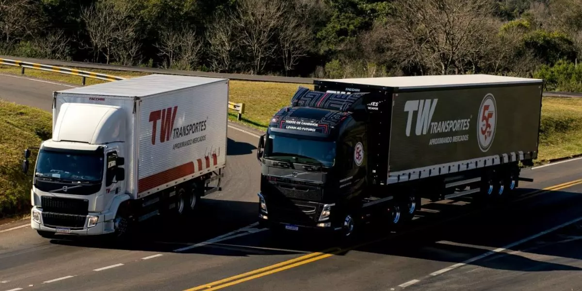 A foto mostra um caminhão e uma carreta da TW Transportes