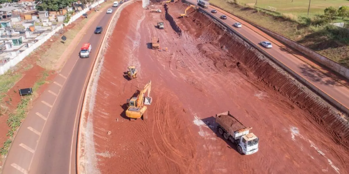 A foto mostra uma obra da CAVA Engenharia com caminhões e máquinas